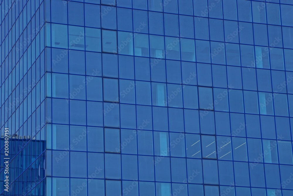 blue glass texture of windows on the wall of a tall building