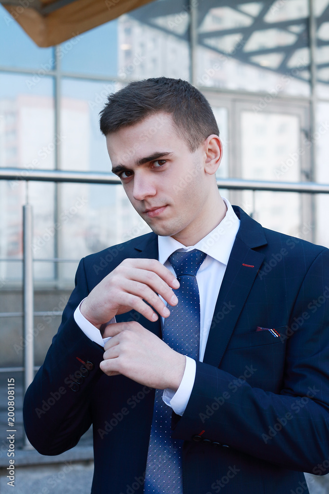 elegant young fashion man looking at his cufflinks while fixing them elegant young fashion man looking at his cufflinks while fixing them