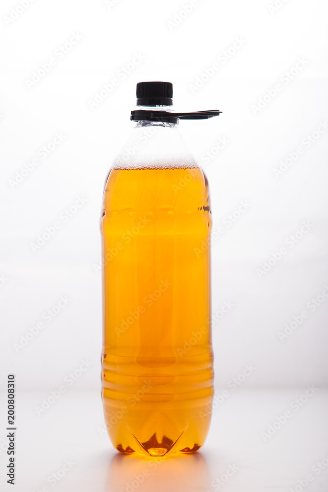 Plastic disposable transparent bottle with a light beer on a clean white background