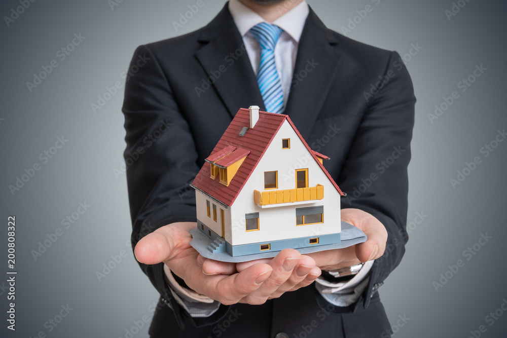 Real estate agent is holding small house in hand. Real estate agent is holding small house in hand.