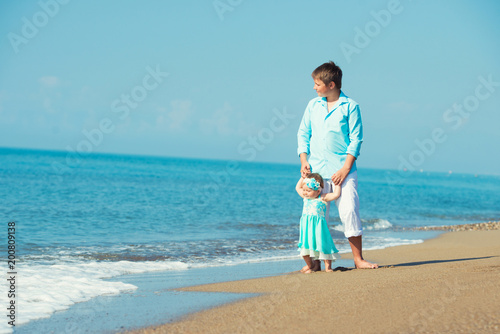 The elder brother walks with his younger sister on the beach. Walking on the beach to see the waves for the first time, family holidays. photo