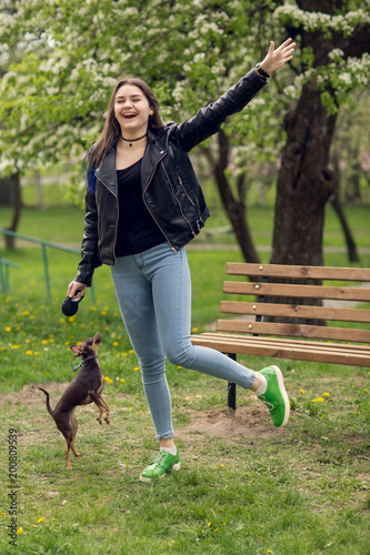 Young beautiful caucasian girl playing with dog russian toy terrier outdoors