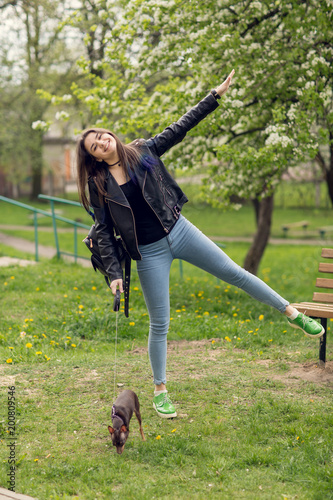 Young beautiful caucasian girl playing with dog russian toy terrier outdoors