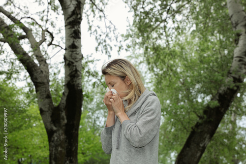 Woman suffering from spring poplar pollen allergy. Sneezing into handkerchief