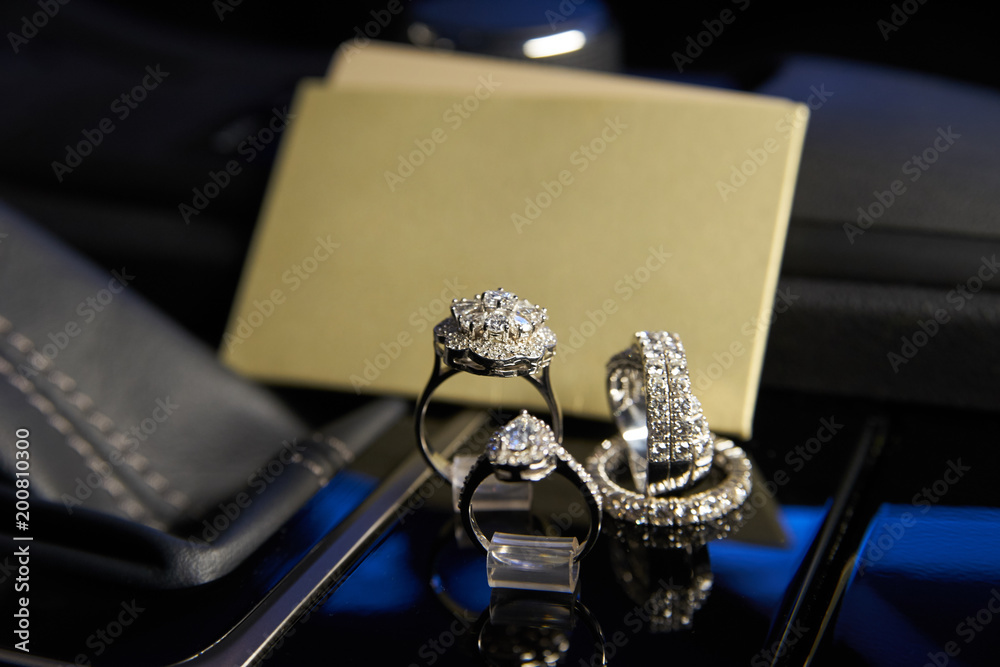 Diamond jewelry rings and earrings in the salon of a luxury car, a gift for women. Empty cards and shopping bag with copy space for your text Diamond jewelry rings and earrings in the salon of a luxury car, a gift for women. Empty cards and shopping bag with copy space for your text