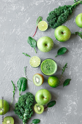 Healthy green smoothie with fresh green fruits, kale and spinach on gray background, top view
