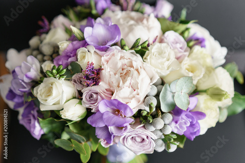 Brides wedding bouquet with peonies, freesia and other flowers on black arm chair. Light and lilac spring color. Morning in room © malkovkosta