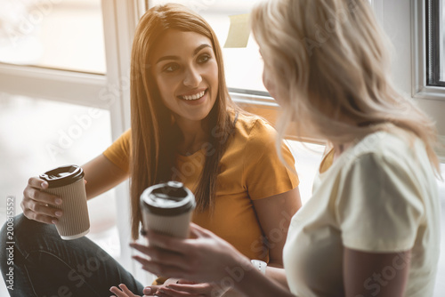 Foto Two glad girls finishing working day with cup of coffee