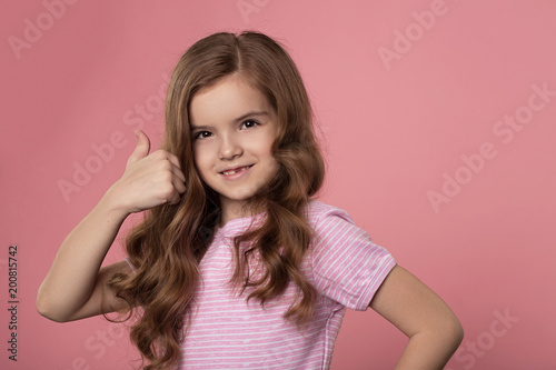 beautiful caucasian girl with bright red hair posing on a pink background. Curly hair of red color