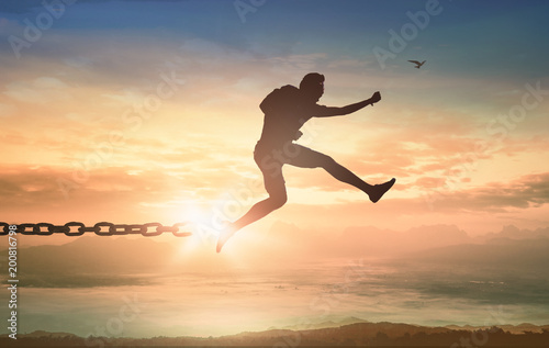 International migrants day concept  Silhouette of human jumping and broken chains at mountain sunset background