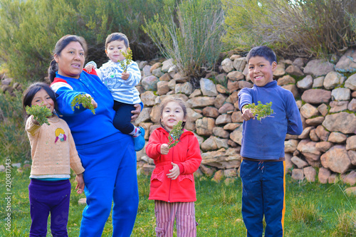Happy native american family showing typical peruvian plant called tipollo. photo