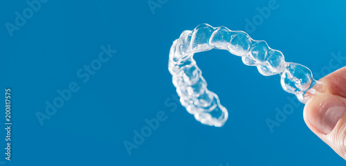 Niewidzialne szelki lub niewidoczny wyrównywacz ortodontyczny.