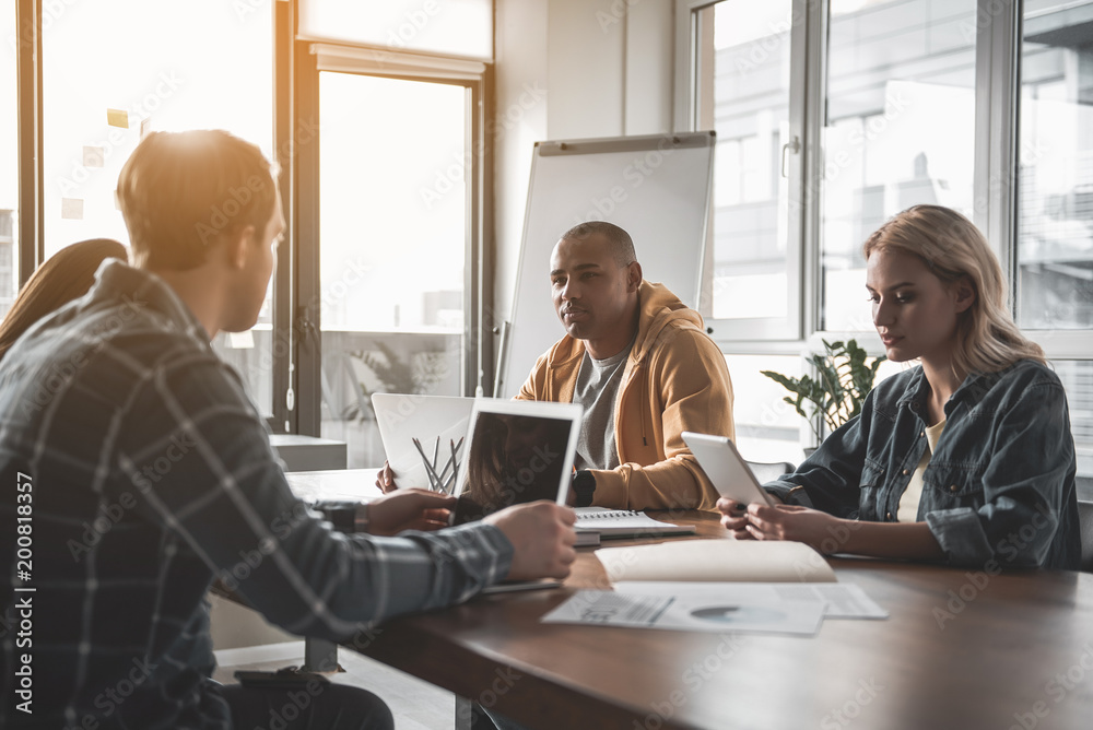 Four calm people sitting at meeting and using gadgets. They having undistracted expressions Four calm people sitting at meeting and using gadgets. They having undistracted expressions