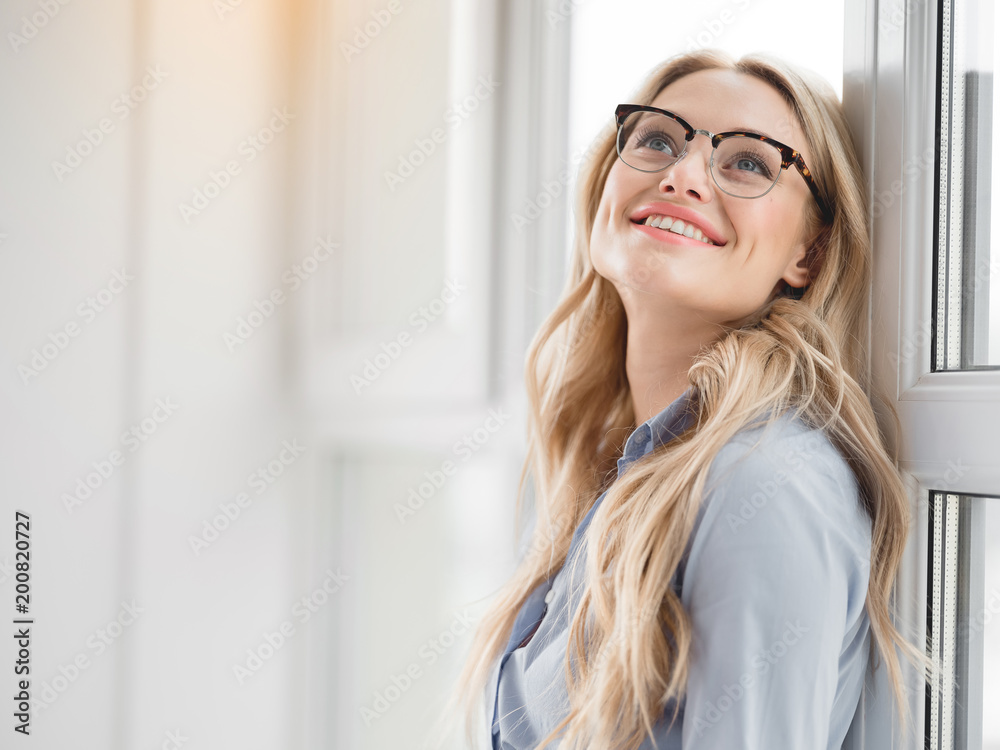 Great day. Portrait of cheerful young woman looking up with happiness and smiling. She is relaxing after work on windowsill. Copy space Great day. Portrait of cheerful young woman looking up with happiness and smiling. She is relaxing after work on windowsill. Copy space