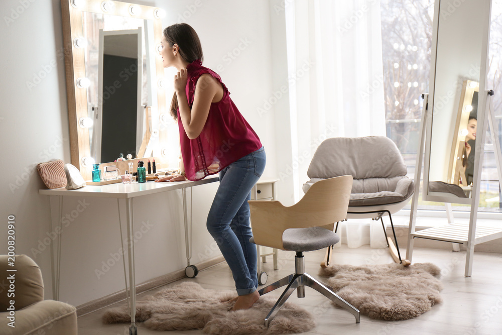 Portrait of beautiful woman with bright makeup near mirror indoors Portrait of beautiful woman with bright makeup near mirror indoors