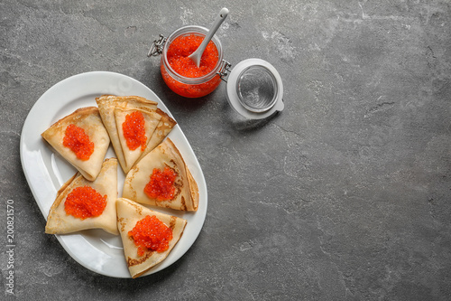 Thin pancakes with delicious red caviar on table