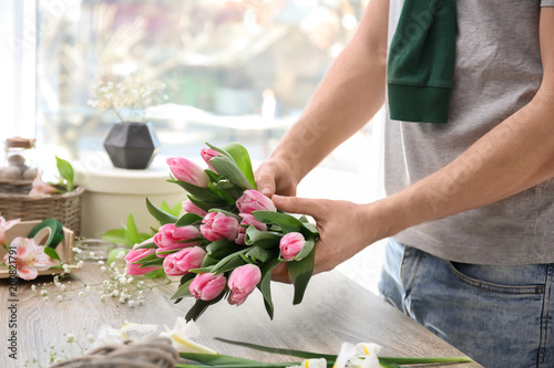 Male decorator creating beautiful bouquet at table