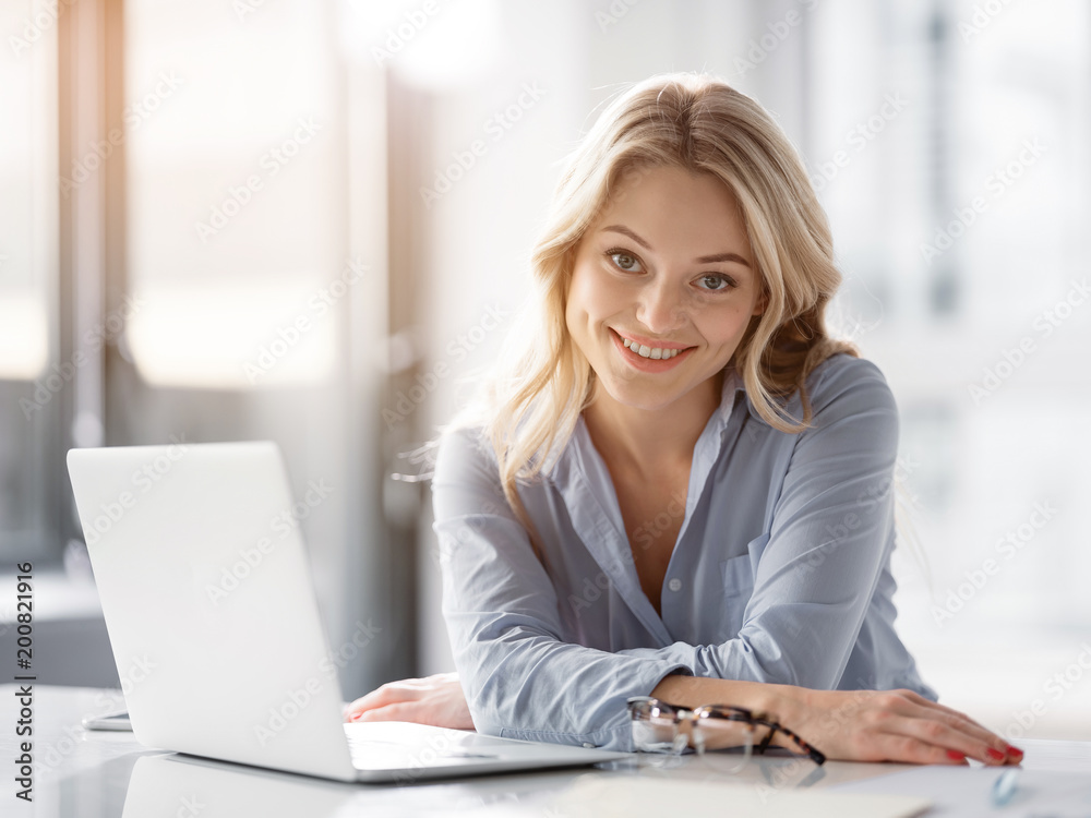 I love my job. Portrait of cheerful young businesswoman sitting at desk and smiling. She is looking at camera with happiness I love my job. Portrait of cheerful young businesswoman sitting at desk and smiling. She is looking at camera with happiness