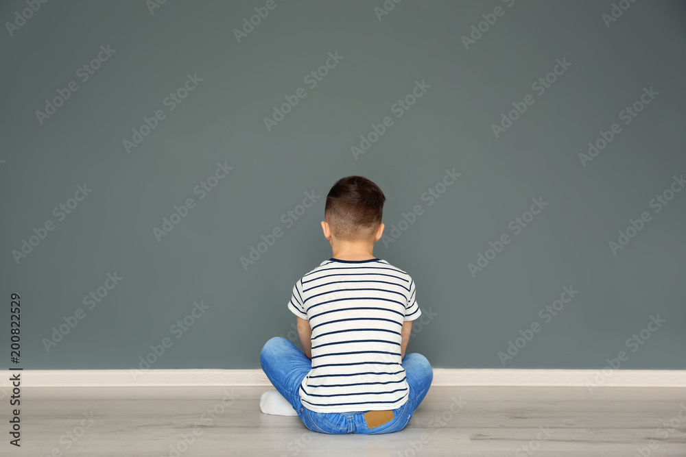 Lonely little boy sitting on floor in room. Autism concept - obrazy, fototapety, plakaty 