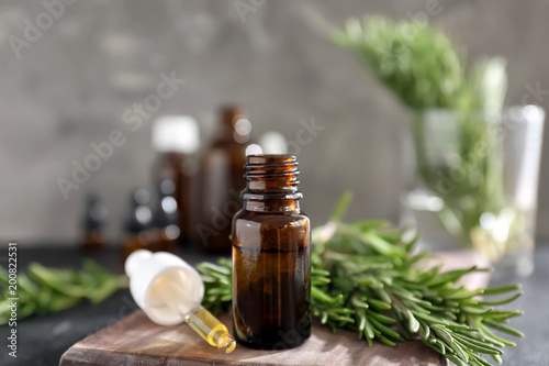 Bottle of rosemary essential oil on wooden board