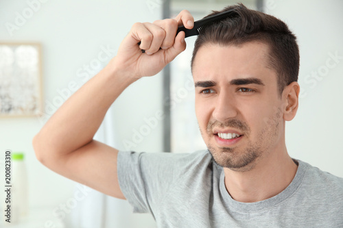 Young man with hair loss problem indoors