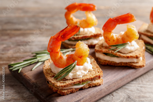 Billede på lærred Delicious small sandwiches with shrimps on wooden board