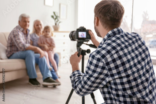Professional photographer taking photo of family on sofa in studio © New Africa