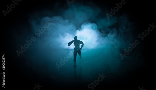 Silhouette of man standing on an dark foggy toned background. Decorated photo with man figure on table with light.
