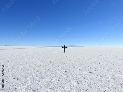 A Tiny Figure in the Vast Landscape of the Salar de Uyuni under a Cloudless Blue Sky, Bolivia