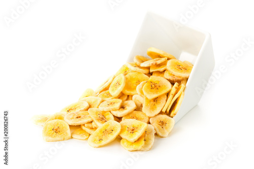 Heap of dried banana chips snack in white bowl over white