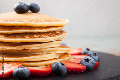 Delicious pancakes close up, with fresh blueberries, strawberries on a light background