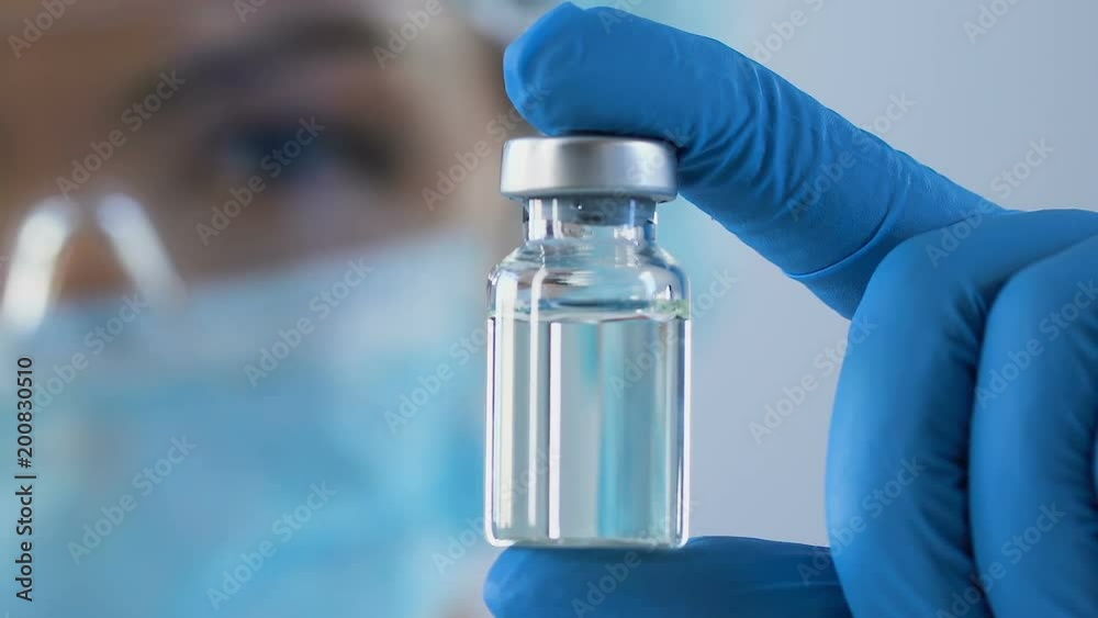 Female scientist carefully examining vial of antidote against dangerous poisons Female scientist carefully examining vial of antidote against dangerous poisons