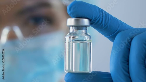 Female scientist carefully examining vial of antidote against dangerous poisons photo