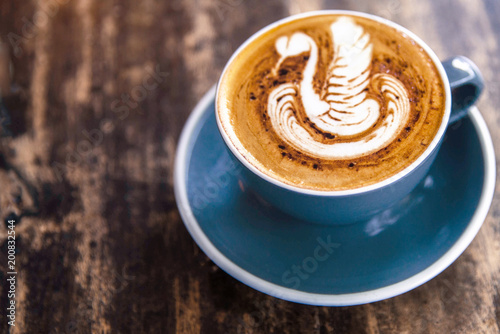 Cup of hot cappucino is on the wooden table