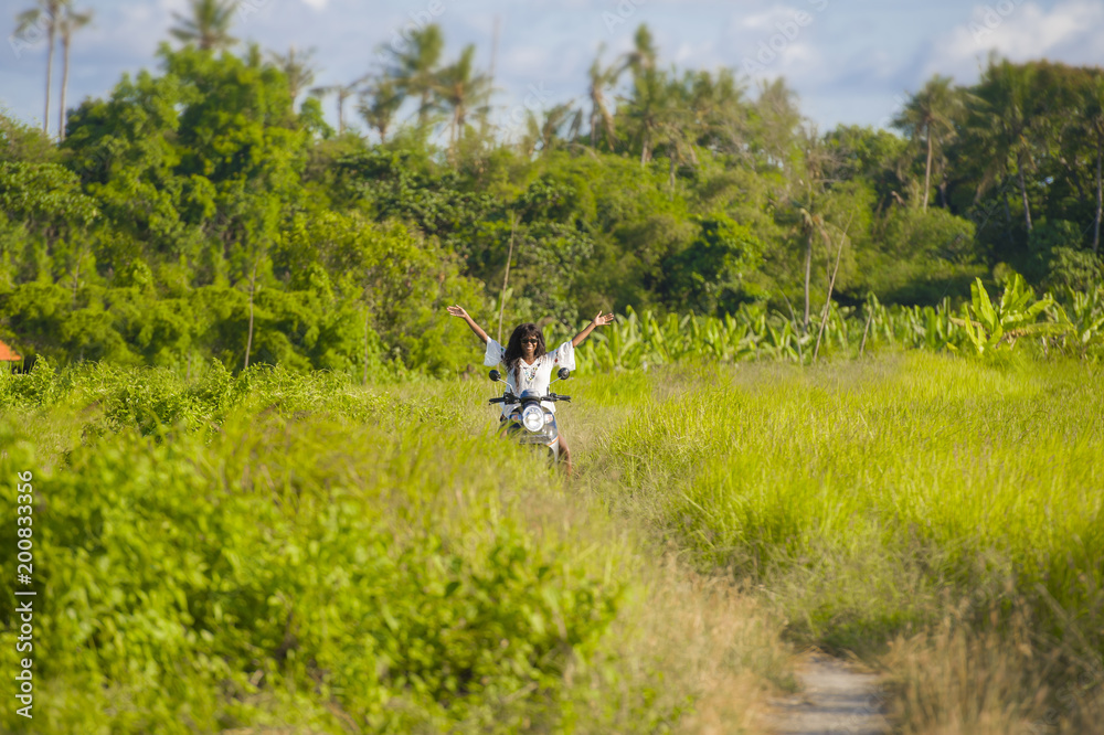 young beautiful tourist or nomad traveler black afro American woman riding motorbike in tropical field wearing traditional Asian hat smiling happy