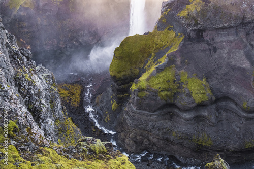 Waterfall in canyon with black rocks and green moss