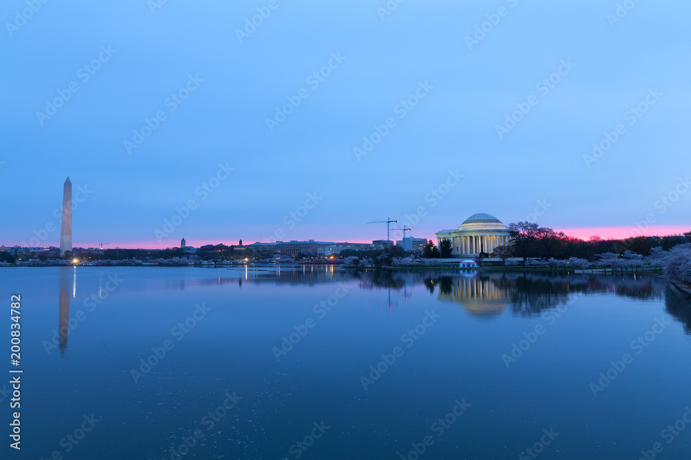 Panorama of cherry blossom around Tidal basin in Washington DC, USA. Flowers abundance at dawn with monuments reflection in still water.