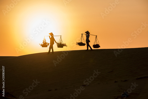 Woman carrying flower basket at sunset in Mui Ne sand dune  Vietnam