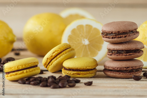 Yellow and brown french macarons with lemons and coffee beans on the wooden board
