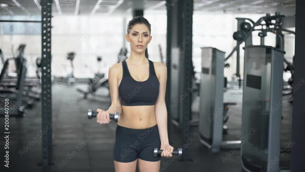 Slim woman lifting dumbbells in gym, arm muscles training, sport lifestyle Slim woman lifting dumbbells in gym, arm muscles training, sport lifestyle