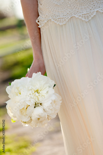 Bride holding wedding bouquet. White peony flowers. Classical elegance. 