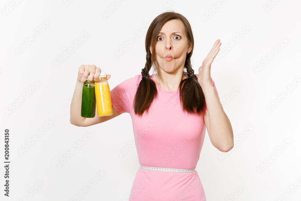 Sad woman holds green, yellow detox smoothies in bottles, measure tape on waist isolated on white background. Proper nutrition, vegetarian drink, healthy lifestyle, dieting concept. Copy space, flack. Sad woman holds green, yellow detox smoothies in bottles, measure tape on waist isolated on white background. Proper nutrition, vegetarian drink, healthy lifestyle, dieting concept. Copy space, flack.