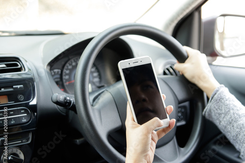 Woman holding mobile phone sending a text while driving a car. Selective focus. © immstudio
