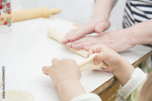 Photography Little boy playing with dough near his grandmother while making donuts