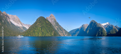 A small boat in the morning at Freshwater Basin in Milford Sound with Mitre Peak and numerous other Mountain Cliffs in Fiordland National Park, New Zealand, South Island.