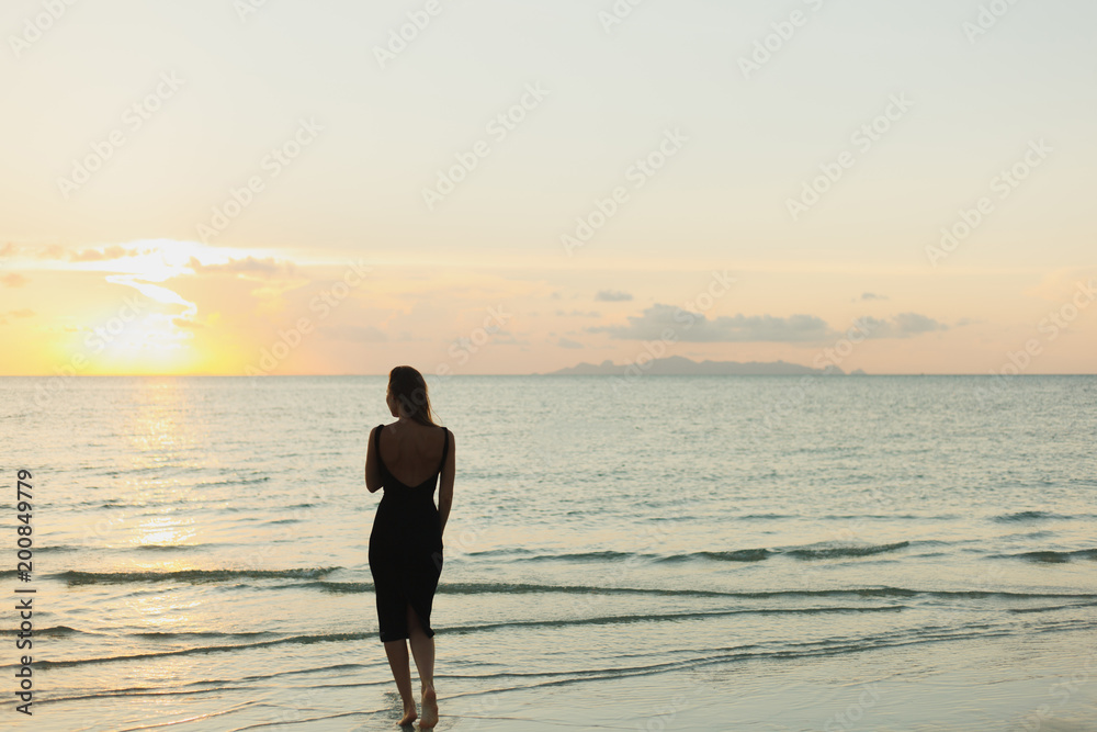 rear view of woman standing in ocean during sunset