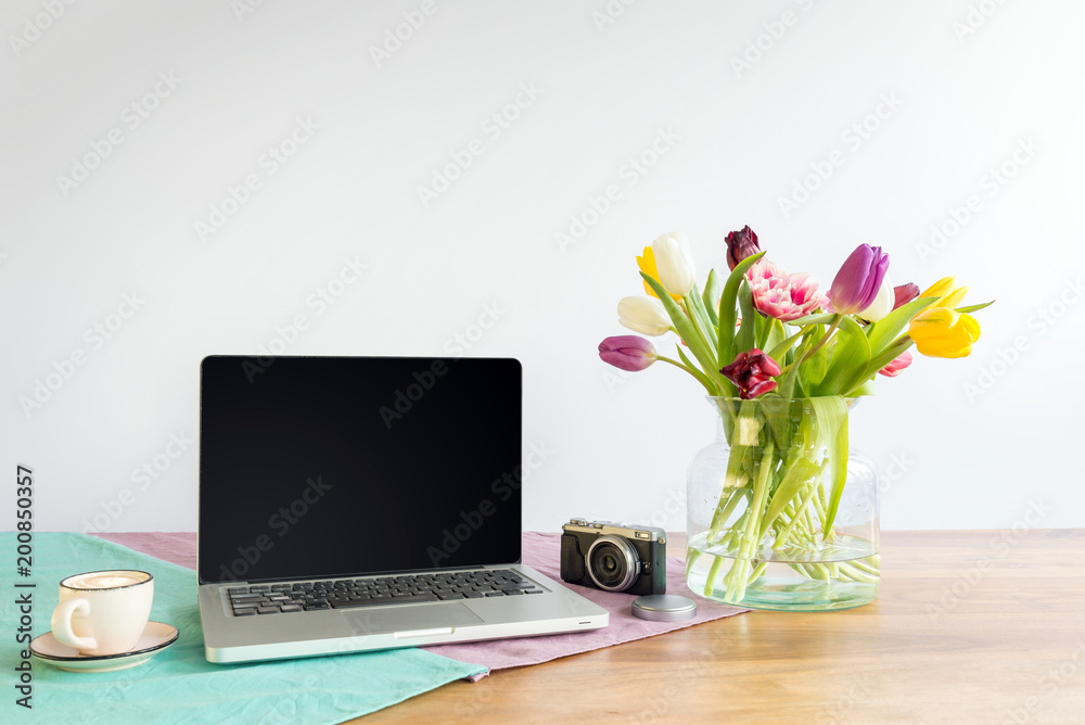 Laptop screen with copy space and flowers on wooden desk with white background Laptop screen with copy space and flowers on wooden desk with white background