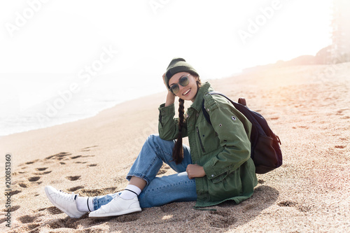 Tourist traveler sitting by ocean sea scape, hipster girl looking on nature horizon, relax holiday.Copy space.woman with backpack coming to ocean to make new photo and enjoy weekend.Stylish girl.