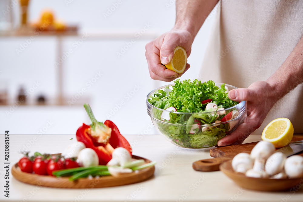 Man cooking at kitchen making healthy vegetable salad, close-up, selective focus. Man cooking at kitchen making healthy vegetable salad, close-up, selective focus.
