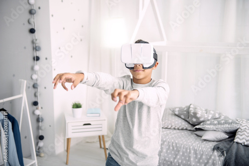 VR world. Cute afro american boy wearing VR headset while rising hands